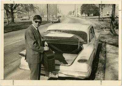 Student with suitcase in front of car